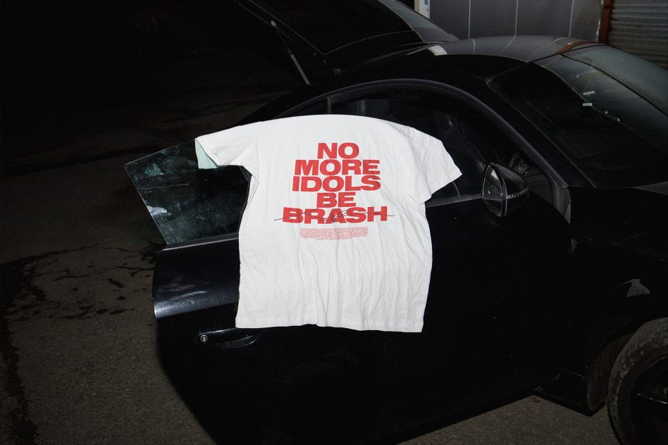 T-shirt with bold red text on white fabric draped over a car door, urban mockup for edgy clothing designs, night setting.